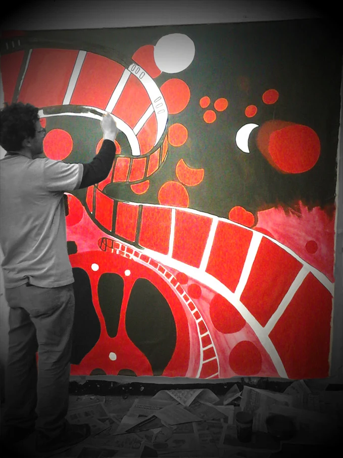Artist painting a red-and-black abstract composition on an interior wall