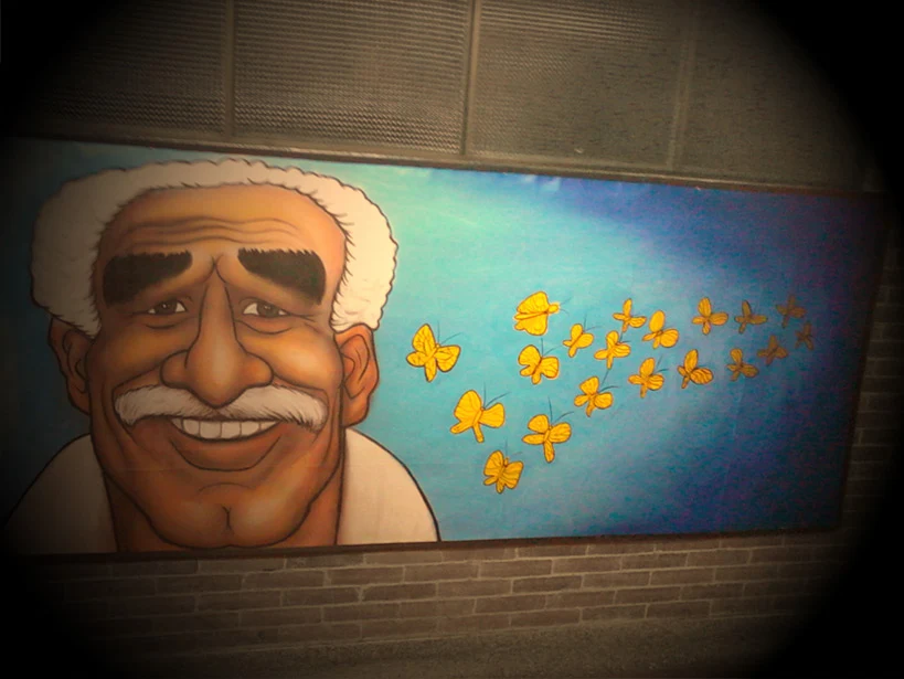 Large smiling portrait mural against a blue background with yellow butterflies